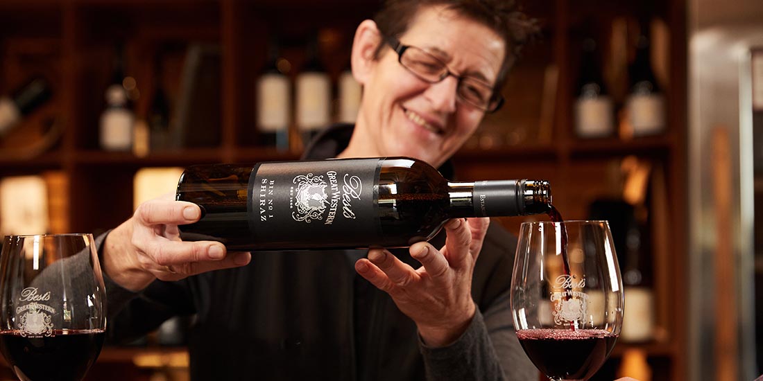 A person pouring wine into wine glasses. 